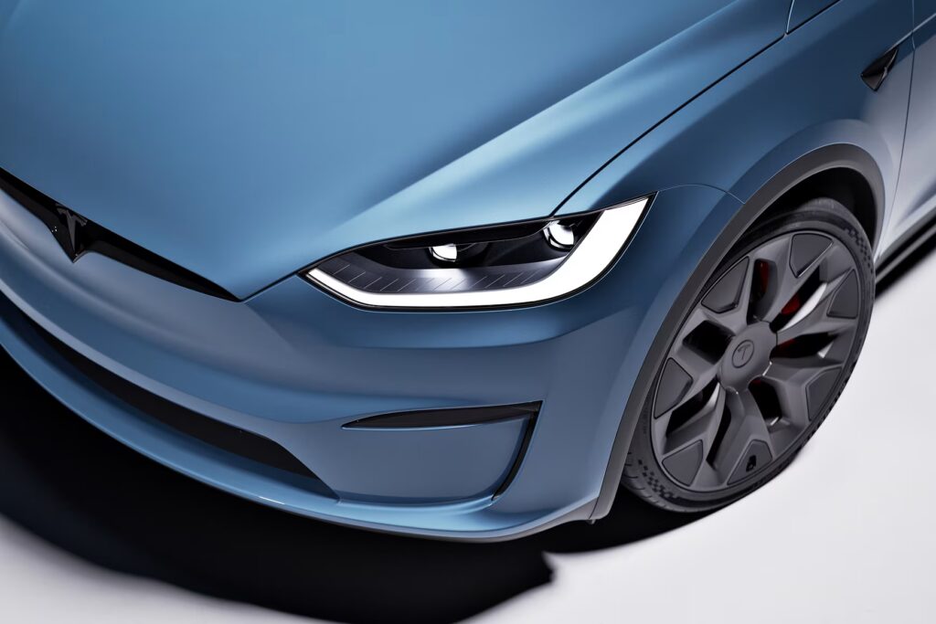 Tesla Model X driving through futuristic city street at sunset – Tesla Model X referral discount activated